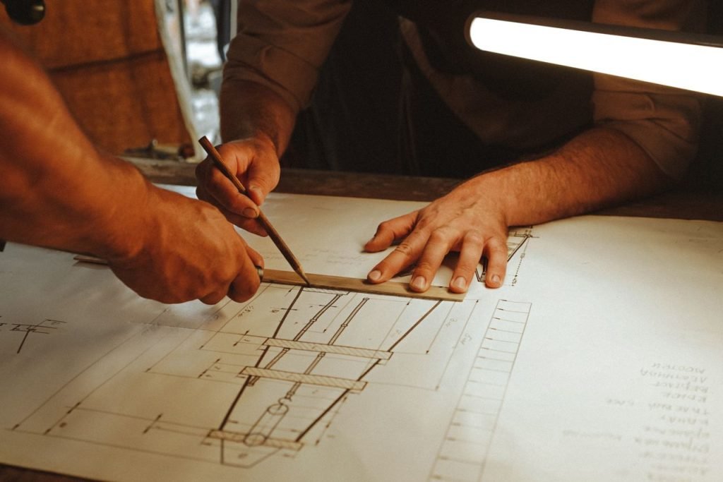 Two architects working together on a blueprint with precision tools under soft lighting.