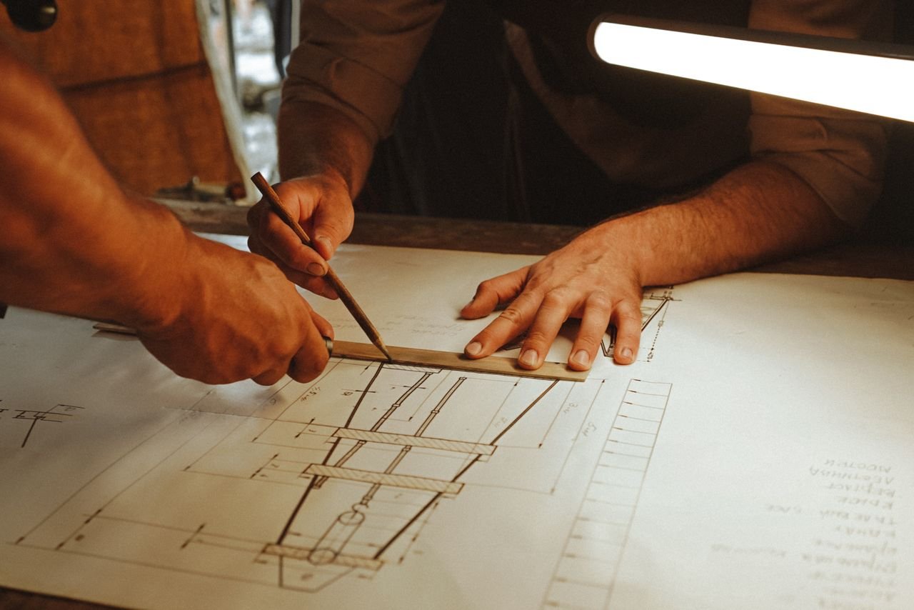 Two architects working together on a blueprint with precision tools under soft lighting.