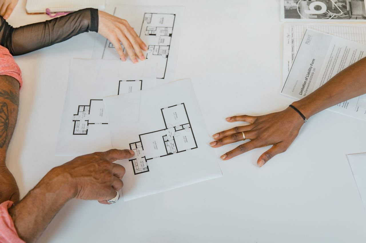 Overhead view of diverse team planning business strategy with floor plans.